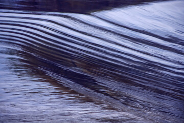 River smooth water flow closeup, down to waterfall