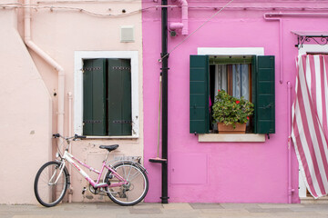 Fototapeta na wymiar Pink houses with brightly painted facades and a matching pink bike leaned against the house in Burano, Venice, Italy