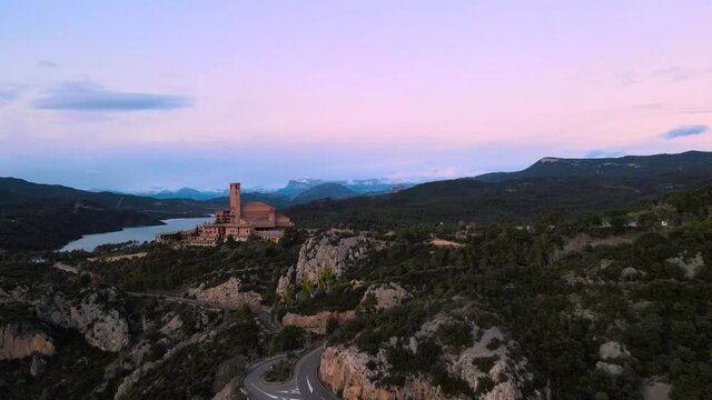 Monasterio sobre la colina en el Pirineo de Huesca. Video aereo del atardecer sobre el monasterio con las monta&ntilde;as nevadas de fondo desde un drone. Plano frontal