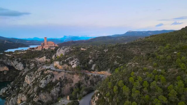 Monasterio sobre la colina en el Pirineo de Huesca. Video a&eacute;reo del atardecer sobre el monasterio con las monta&ntilde;as nevadas de fondo desde un drone. Plano lateral