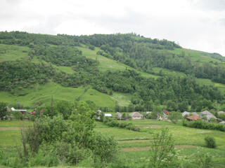 Fototapeta premium village in the valley of mountains. Scenic view of village in the mountains on a cloudy day.