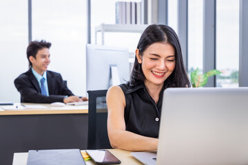 Young Asian woman sitting at office desk and working with laptop computer. Businesspeople or salary man life.