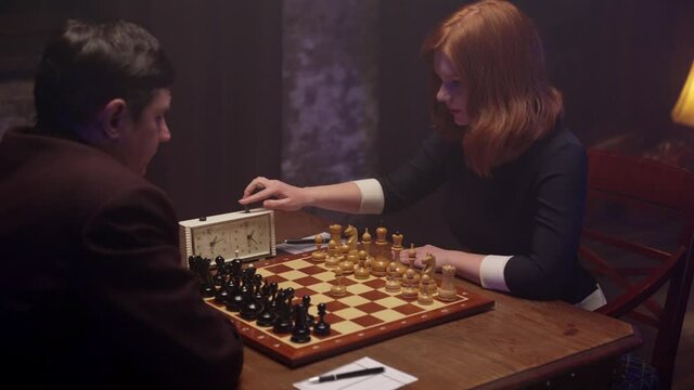 Two chess players man and woman play chess. Debut Accepted Queen's Gambit, King's Gambit, Philidor's Defense. Cinematic filming of a chess game. Antique chess board. This shot can be used for films.