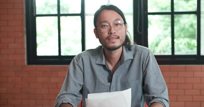 POV of A young, confident, beautiful Asian businessman or manager makes the conference video call and listening & nodding to a colleague speaking in the conference room at warehouse offices.