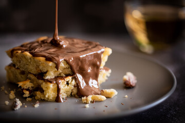 Melted chocolate pouring on cake with nuts