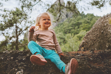 Child eating cookies outdoor in forest travel family vacation baby girl on picnic healthy lifestyle