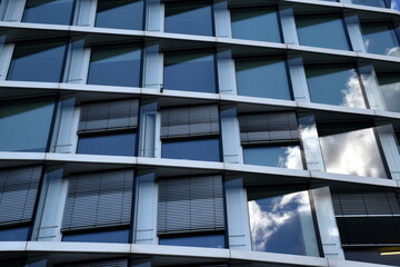 Wolken spiegeln sich in einer modernen Bürofassade