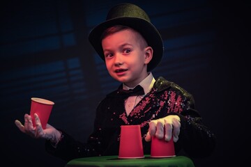 Magician kid illusionist boy in hat. childhood isolated black background