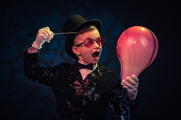 Balloon and Magician kid illusionist boy in hat. mystery trick isolated black background
