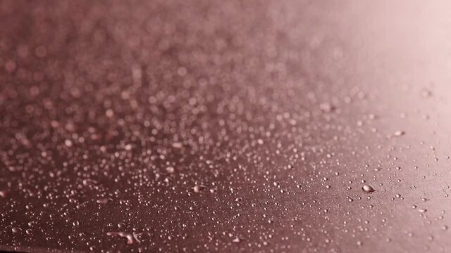 Copper. Metal plates. Drops of water are sprayed onto copper coating. Copper oxidation process. Chemical reaction a copper plate interacts with an oxidizing agent. 