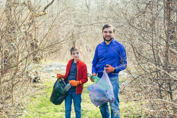 Naklejka na ściany i meble Father and son clean the park of rubbish, volunteers clean the forest of plastic bottles, and spend time together