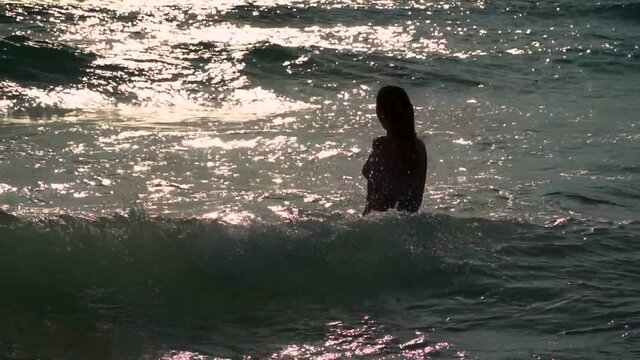 woman was covered by a wave in the sea. A man swims in sea and falls under a tsunami wave. bras are covered with a man's head under the water Silhouette of a woman in the sea.