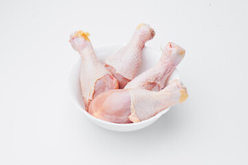 Raw chicken legs on a white plate isolated on a white background. Close-up.