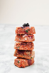 Composition with raw square cutlets on light background. Natural food for dogs. BARF dog diet. Close up