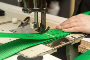 Industrial sewing machine sews a webbing sling. Manufacture of textile slings and tie straps.