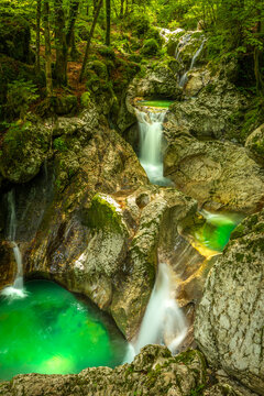 Beautiful water cascades or small waterfall in the valley of Lepena in Slovenian Julian Alps. Emerald green waterfalls in an enchanted forest.