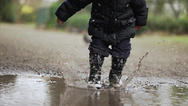 Child jumping into puddle of water in slow-motion 240fps