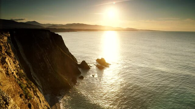 Sunset over rocky cliffs at Asturias coast in north Spain. View from Faro de Cabo Busto. Tourist attraction, place to visit.