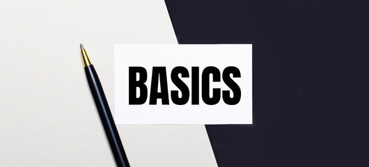 On a black and white background lies a pen and a white card with the text BASICS