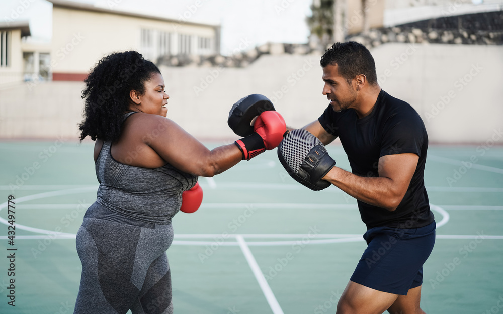 Wall mural Curvy african girl and personal trainer doing boxing workout session outdoor - Main focus on coach face