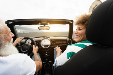 Happy senior couple having fun in convertible car during summer vacation - Travel and joyful...