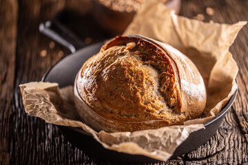 Crusty yeast bread loaf made lying on the baking paper in the rustic alloy pan