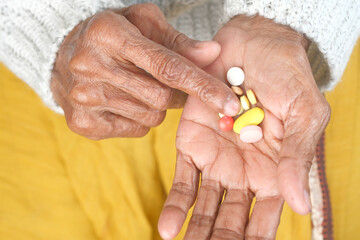close up of pills and capsule on senior women's hand 