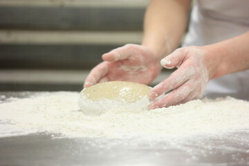 Woman's hands kneading the bread dough. Making dough by female hands on wooden table