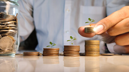 Hand putting coin on coin stack growing graph with business man  background, investment concept. tree growing on coin, Business Finance and Save Money concept
