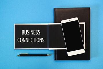 A white notebook with black pages, a smartphone and a pen on a blue background. The inscription Business Connections