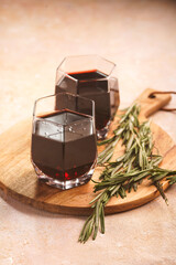 Mulled wine in hexagonal glasses with rosemary and cinnamon on a round wooden board