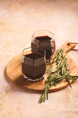 Mulled wine in hexagonal glasses with rosemary and cinnamon on a round wooden board