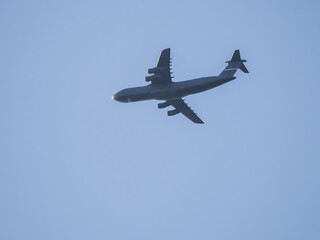 Big military four-engine airplane flying in blue sky