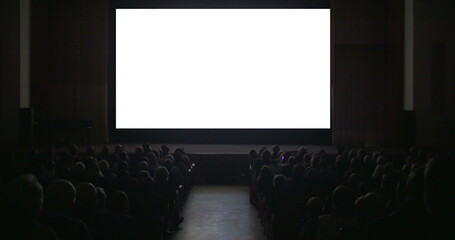 Viewers in dark cinema hall with blank screen