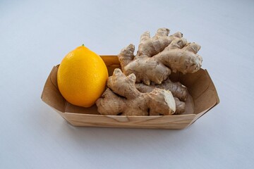 Fototapeta na wymiar Large ripe lemon and a branch of ginger in a wooden box