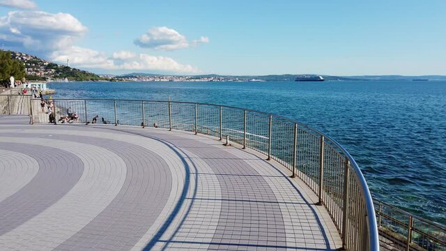 Terrace on the Barcola seafront in Trieste, Italy, during a glorious springtime afternoon, with the city skyline in the background