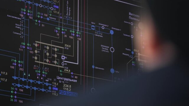 Operator controls equipment looking at black screen with circuit schemes in control room of production plant extreme closeup