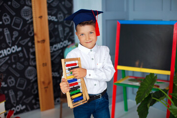 Portrait of smiling student in graduation cap holding abacus in class