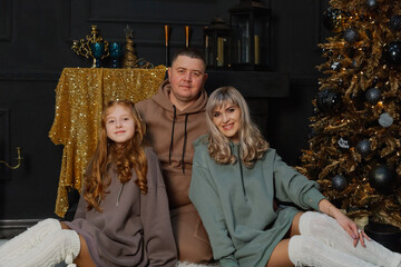 Happy family on the floor by the Christmas tree.