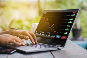 A business man is checking daily online stock market prices through a laptop at home with graphs...