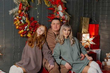 Beautiful and happy family at the New Year tree at a photo shoot.