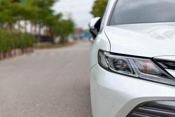 A white car parked on the roadside with a natural background.