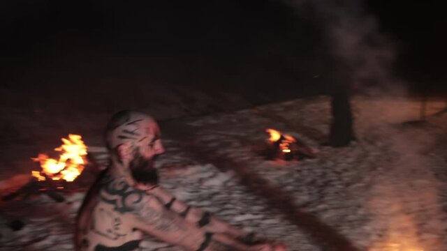 Battle an evil aggressive viking warrior in northern tattoos with a bare torso on burning fire swords with an opponent from our days wearing glasses