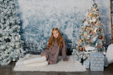 Beautiful teenage girl on the floor by the Christmas tree.