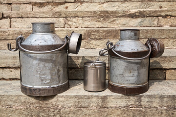Metal milk jugs on stone steps in India/Pushka. The most popular drink in India is the famous chai, tea with milk or milk tea, available on every street corner, prepared on small stoves. Day.