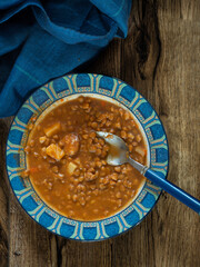Lentil soup in a plate on wood background
