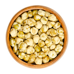 Crunchy green peas, in a wooden bowl. Salted green peas in a crispy cover of maize starch. A wholesome, vegan and low fat snack. Close-up, from above, isolated, on white background, macro food photo.