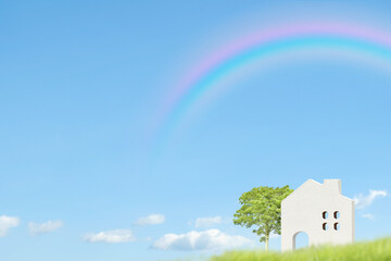 虹がかかった青空の背景に緑と白い家