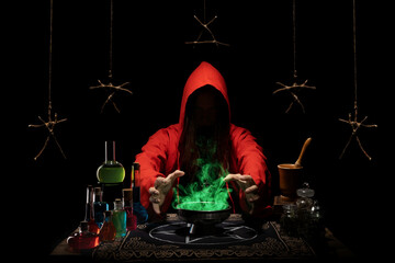 The medieval alchemist make magic ritual at the table in his laboratory. A red-robed, hooded mage.
