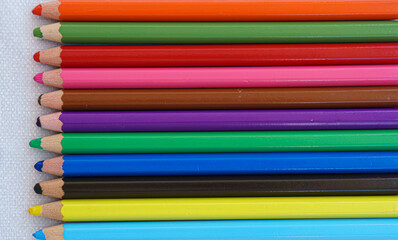 Colorful art pencils for dry painting. Green, red, blue, yellow, orange, pink art pencils on white table.
